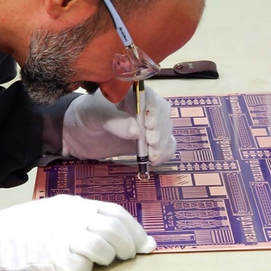 Atotech-Mitarbeiter begutachtet Leiterplatte nach Kupferabscheidung mit einem Handmikroskop